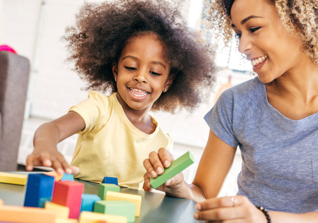 child and adult play with blocks